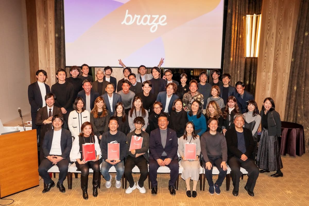 a large group of people are posing for a picture in front of a large screen .