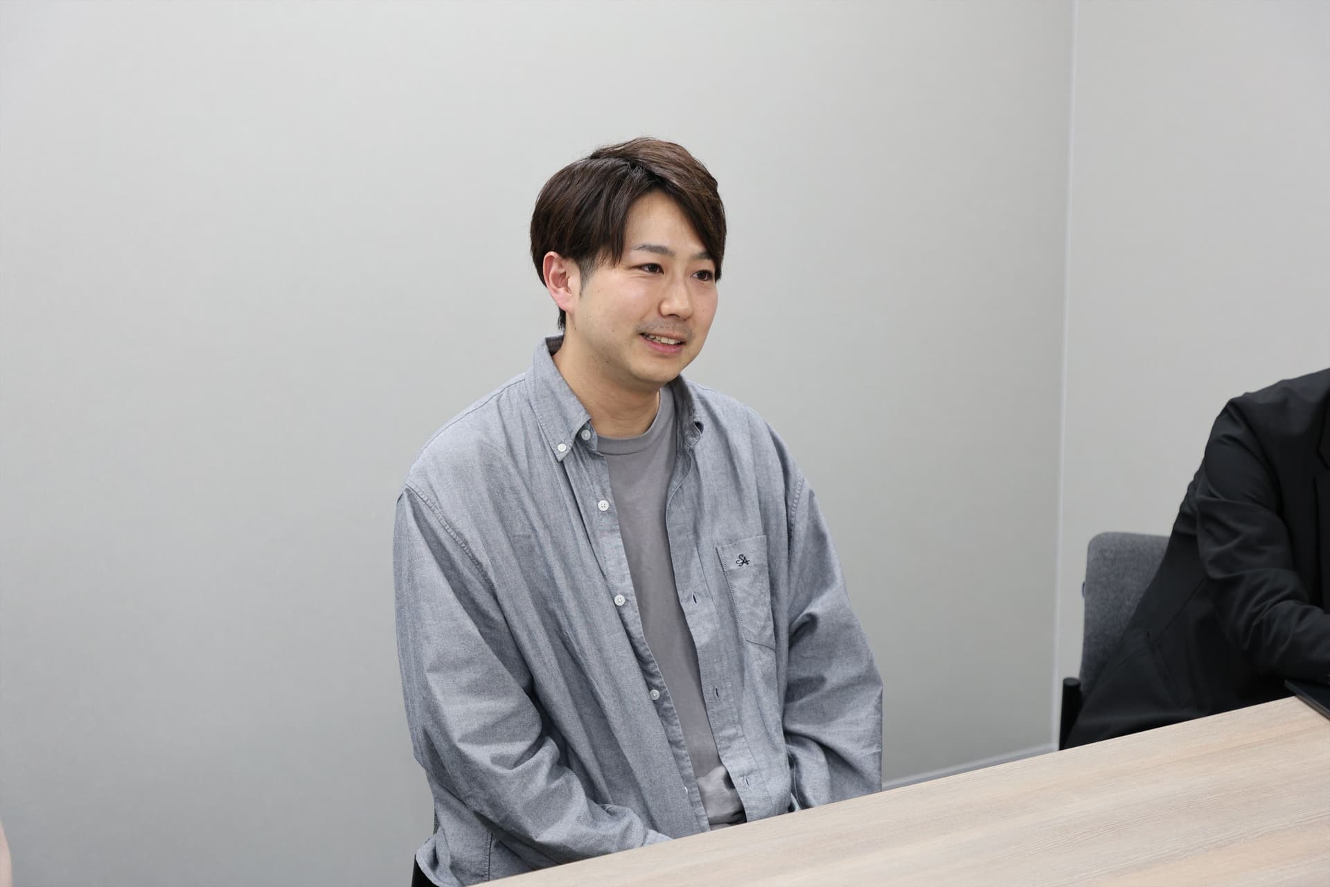 OMO本部マーケティング部マネジャー 白倉 鉄平氏がインタビューを受けている様子。グレーシャツをきていて笑顔で話をしている