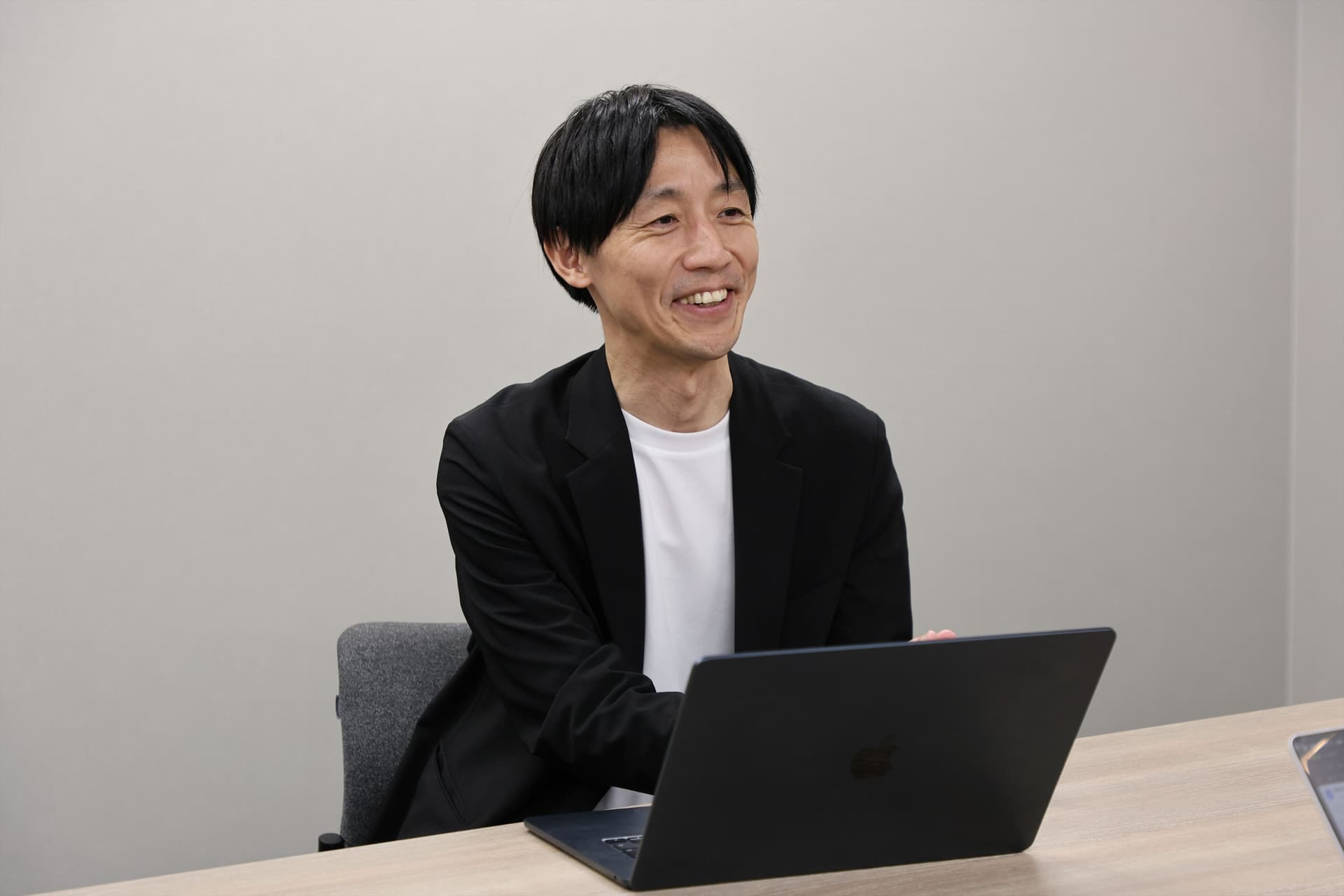 CDO兼マーケティング部ゼネラルマネジャー 坂本 武史氏がインタビューを受けている様子。PCを前に笑顔で話をしている