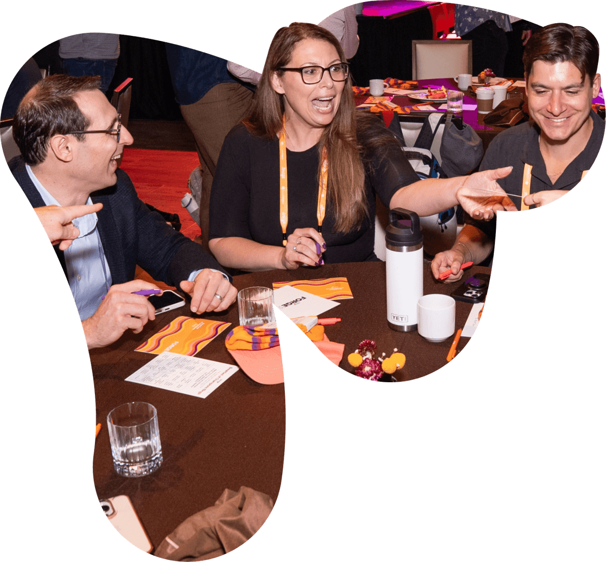 Three smiling people engaged in conversation around a table at an event.