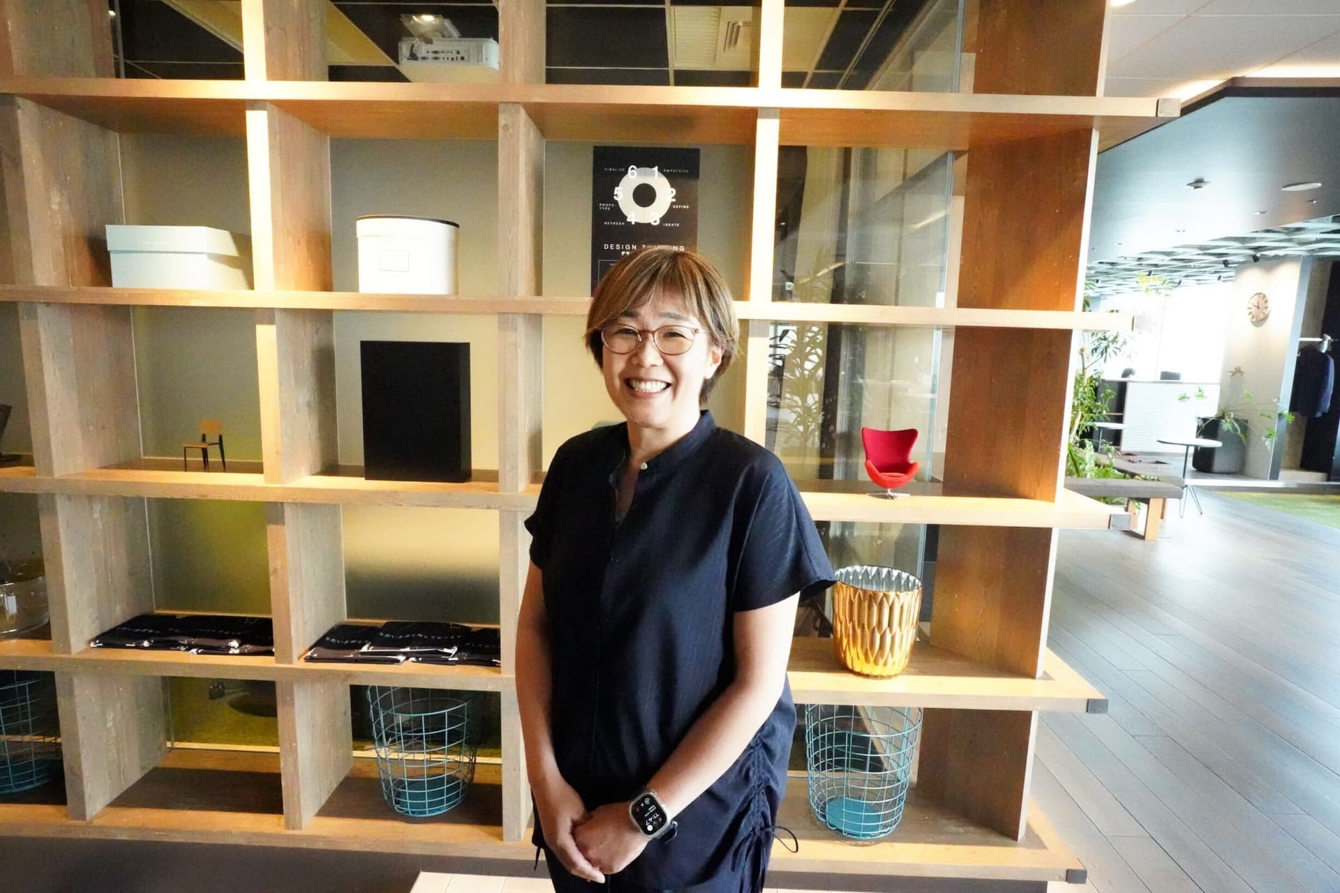 a woman is standing in front of a bookshelf and smiling .