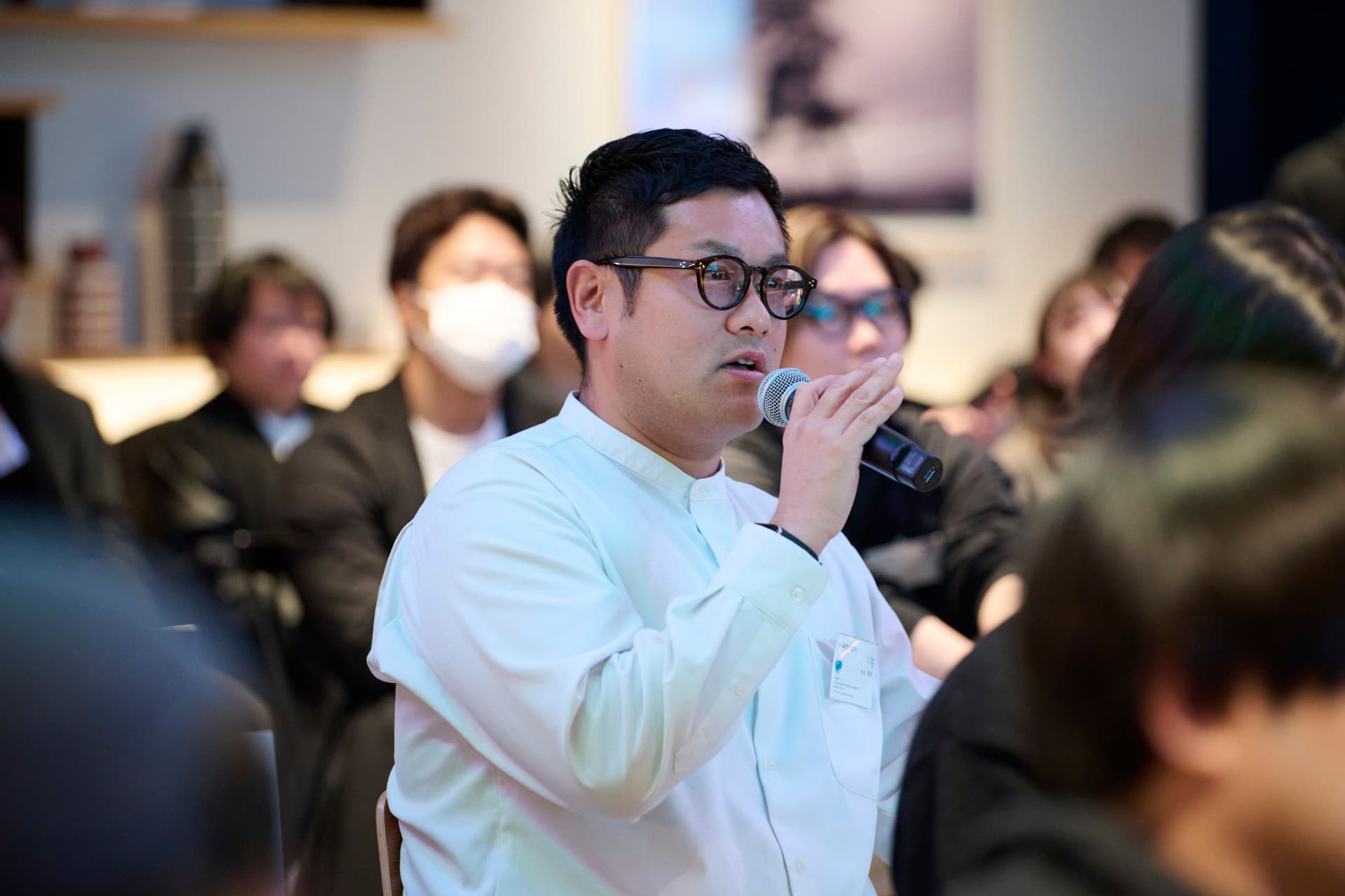 a man is holding a microphone in front of a crowd of people .