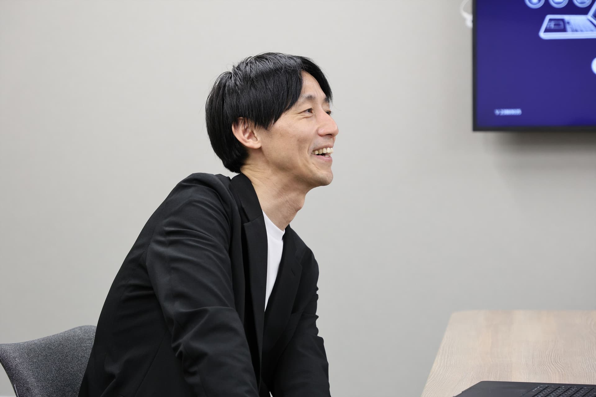 サツドラホールディングス株式会社 CDO兼株式会社サッポロドラッグストアー OMO本部本部長兼マーケティング部ゼネラルマネージャーの坂本 武史さんがインタビューを受けている様子。笑顔で話をしている