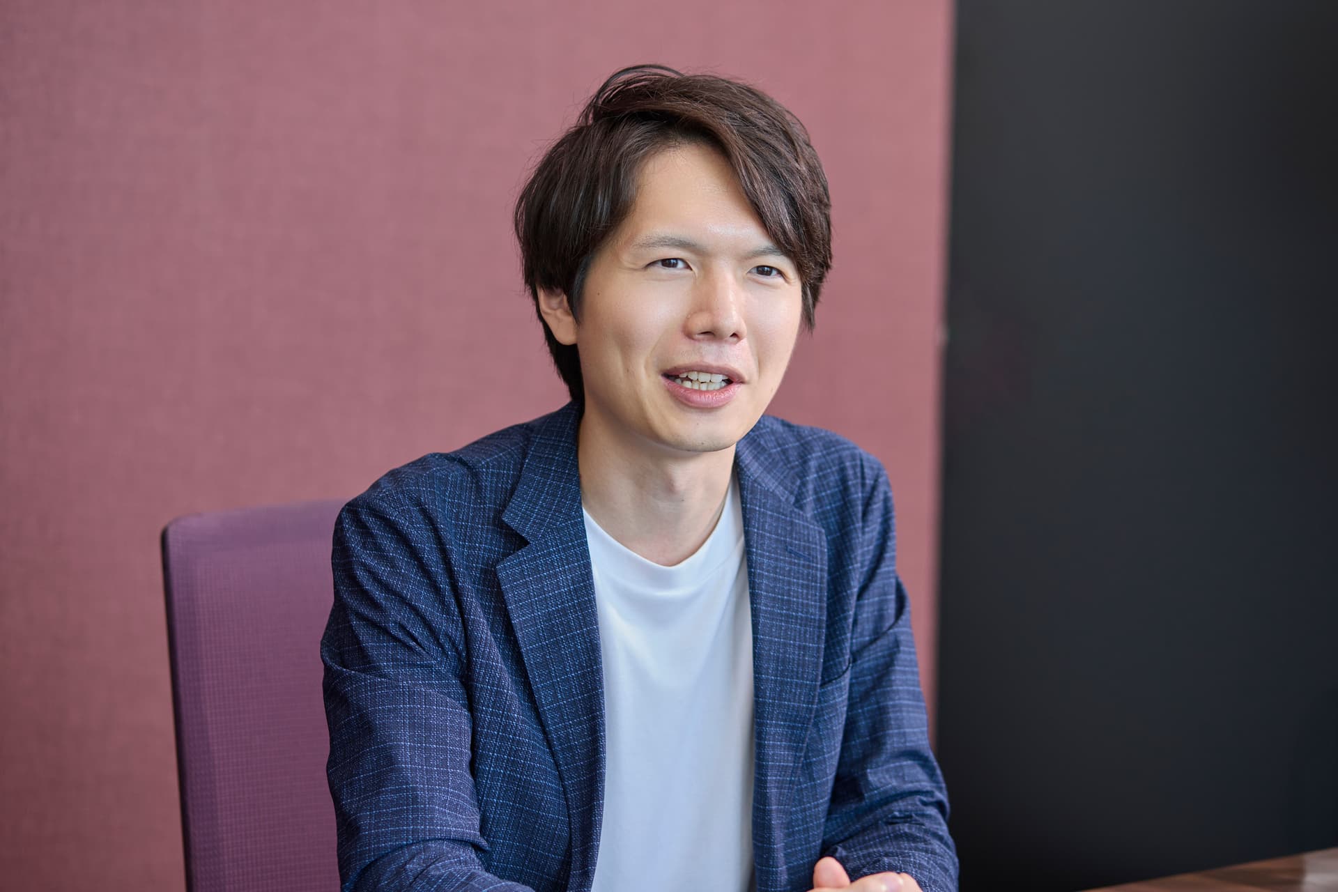 a man in a blue jacket and white shirt is sitting in a chair .