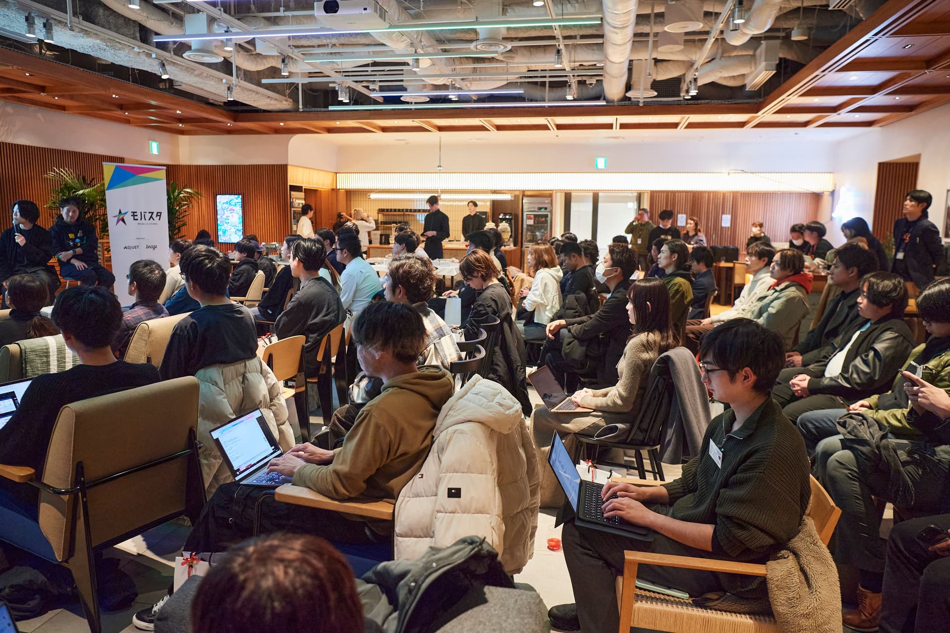 a large group of people are sitting in chairs in a room using laptops .
