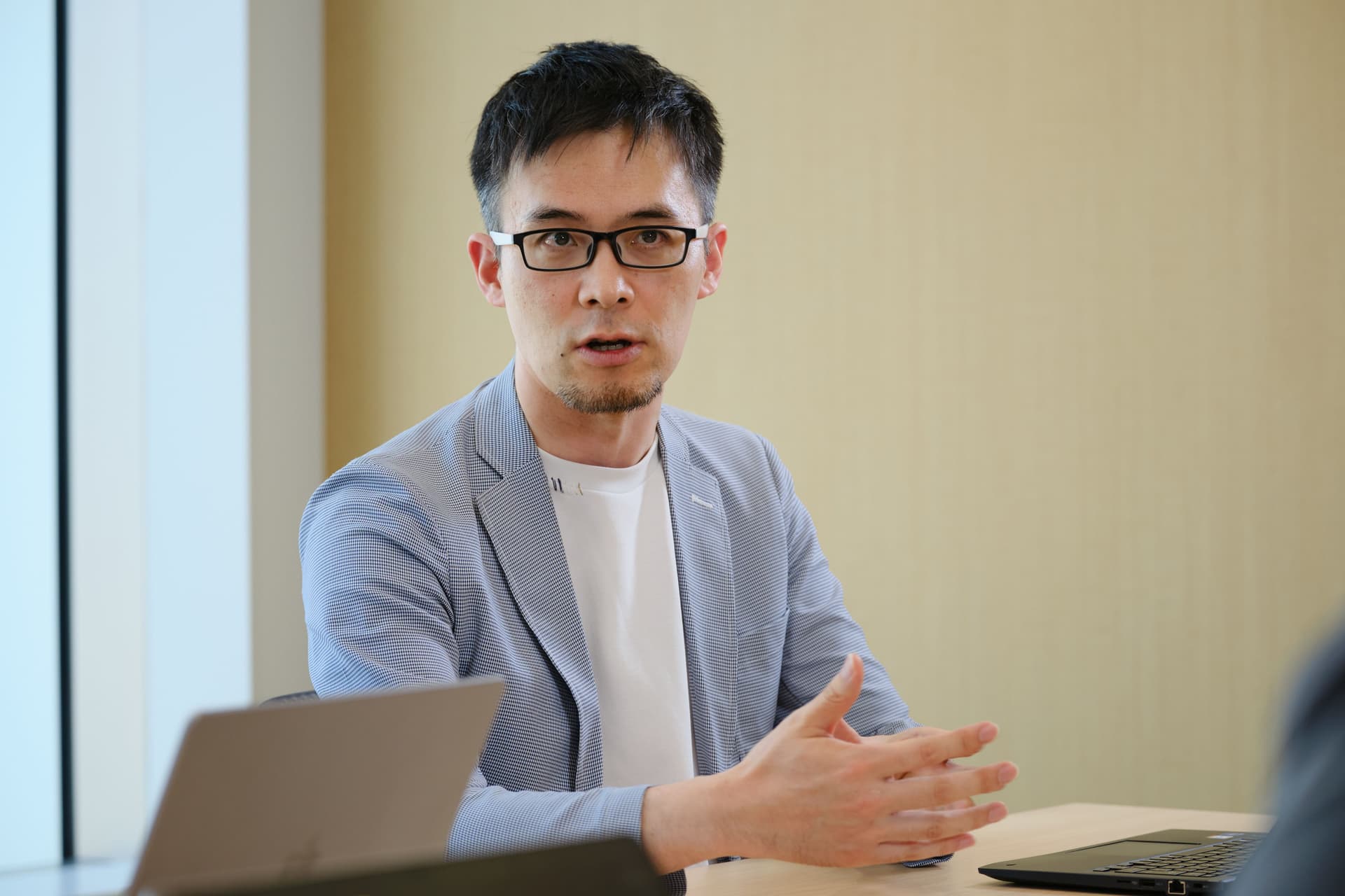 a man wearing glasses is sitting at a table with a laptop .
