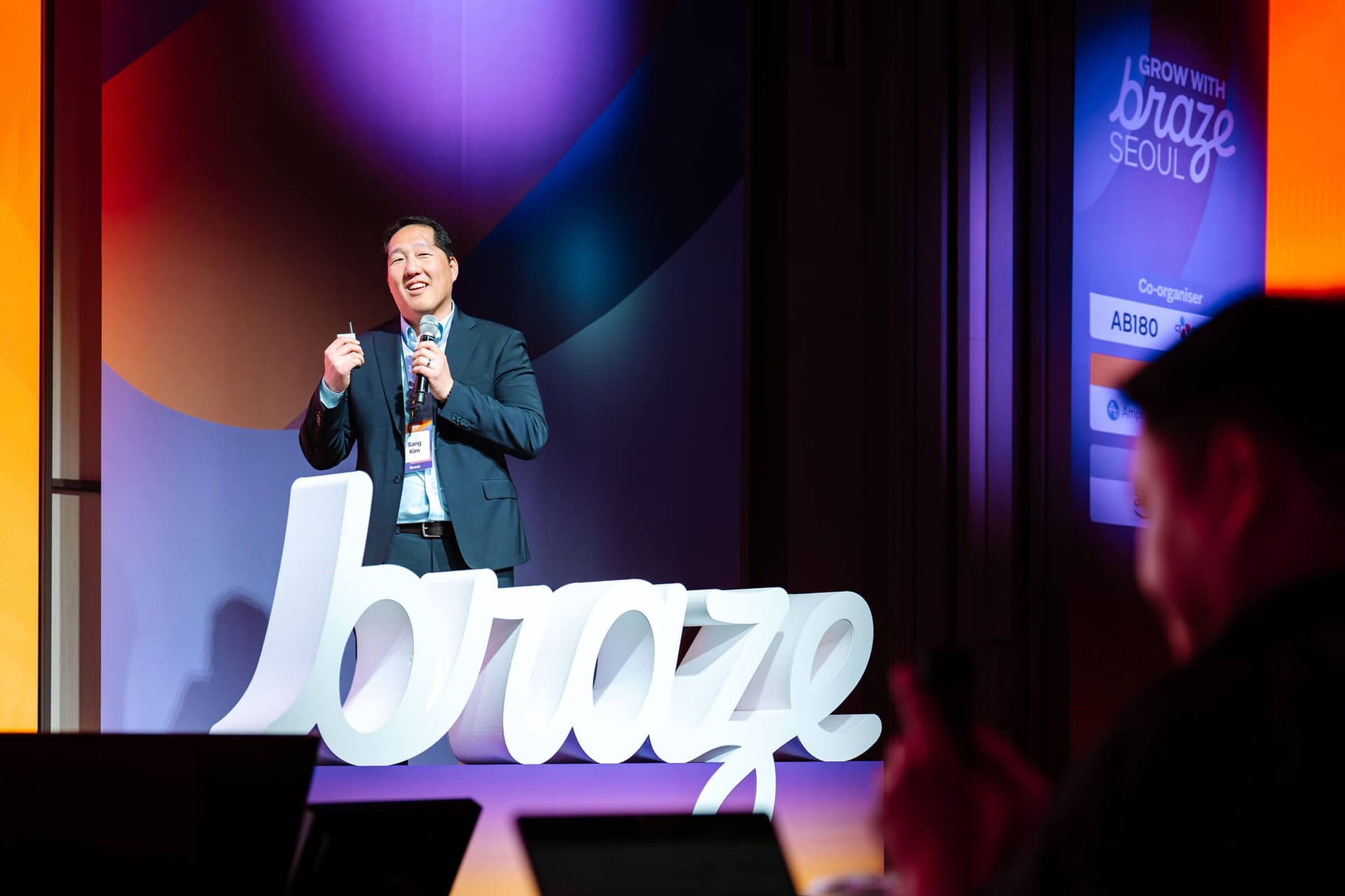 Man speaking on stage at a "Grow with Braze Seoul" event, with a large "braze" logo in front.