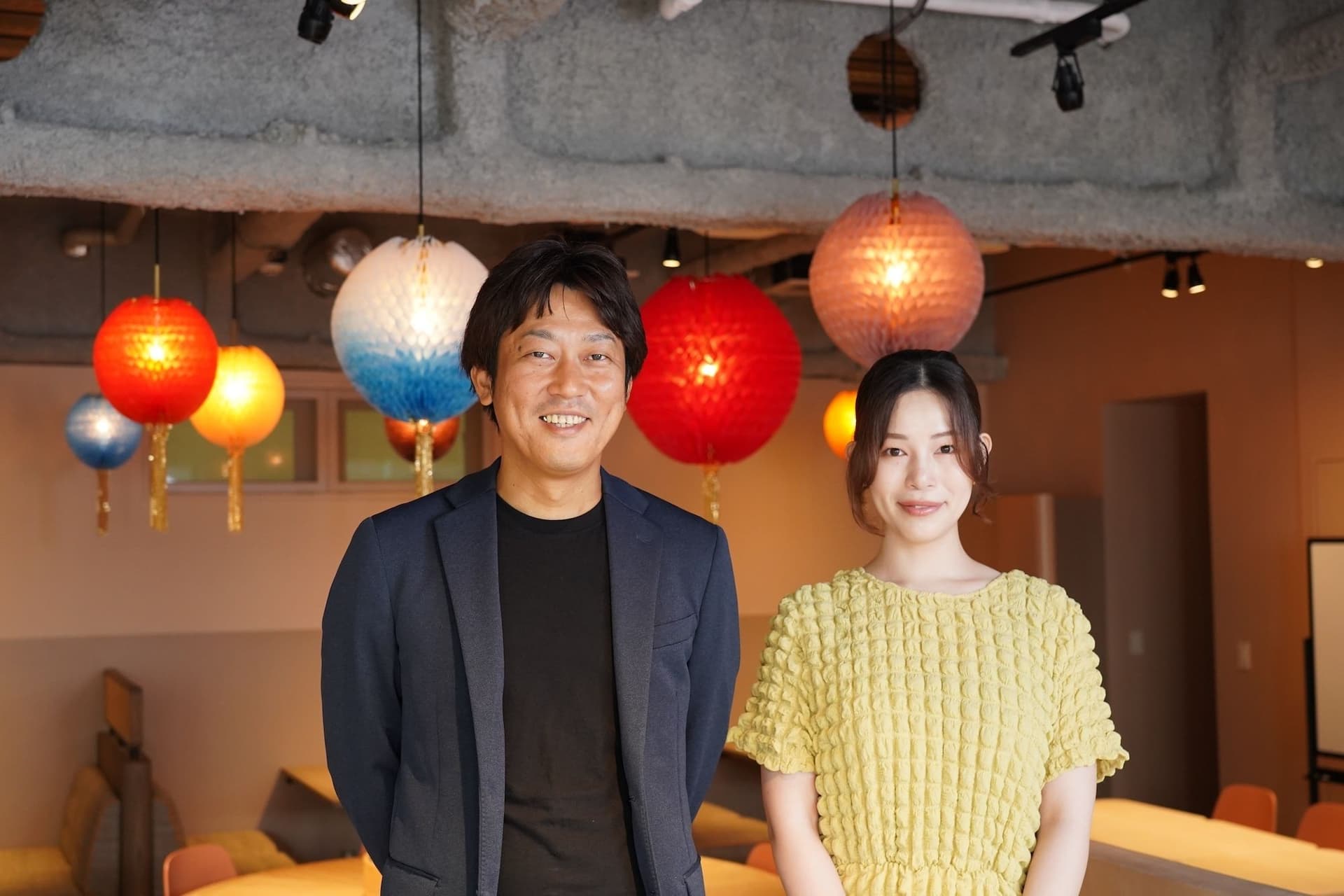 a man and a woman are standing next to each other in a room with lanterns hanging from the ceiling .