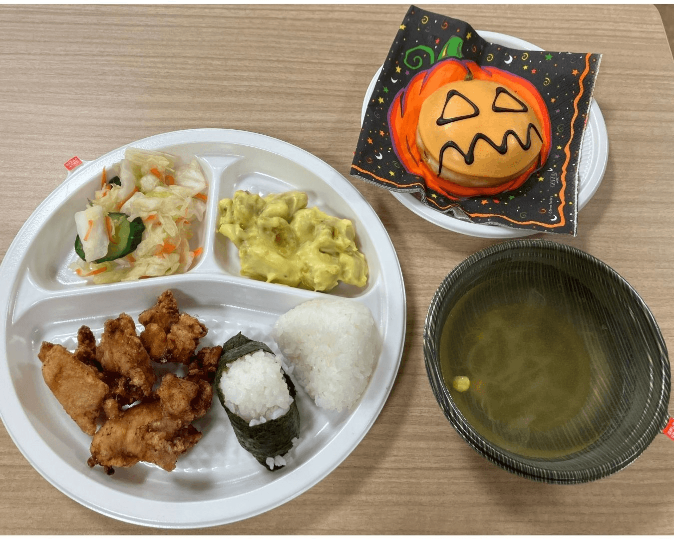 A Halloween-themed meal with fried chicken, rice, two salads, soup, and a pumpkin donut.