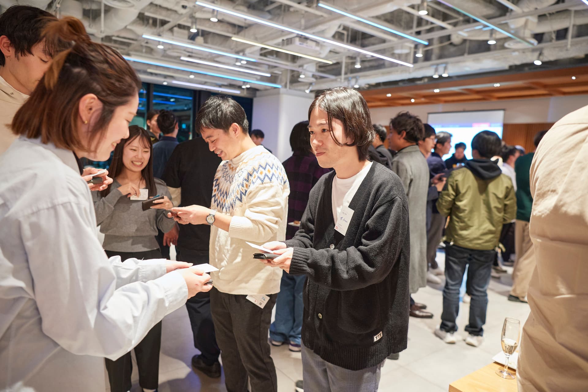 a group of people are standing in a room talking to each other .