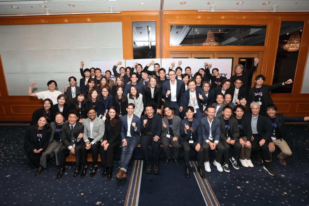A large team enthusiastically raises their fists for a group photo.