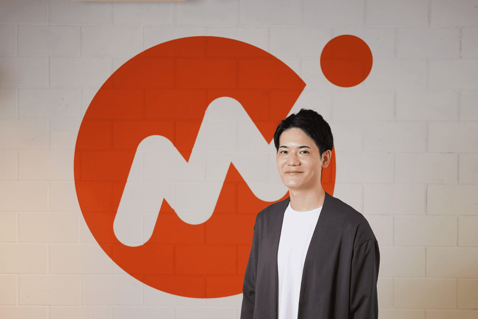 a man stands in front of a large m on a brick wall