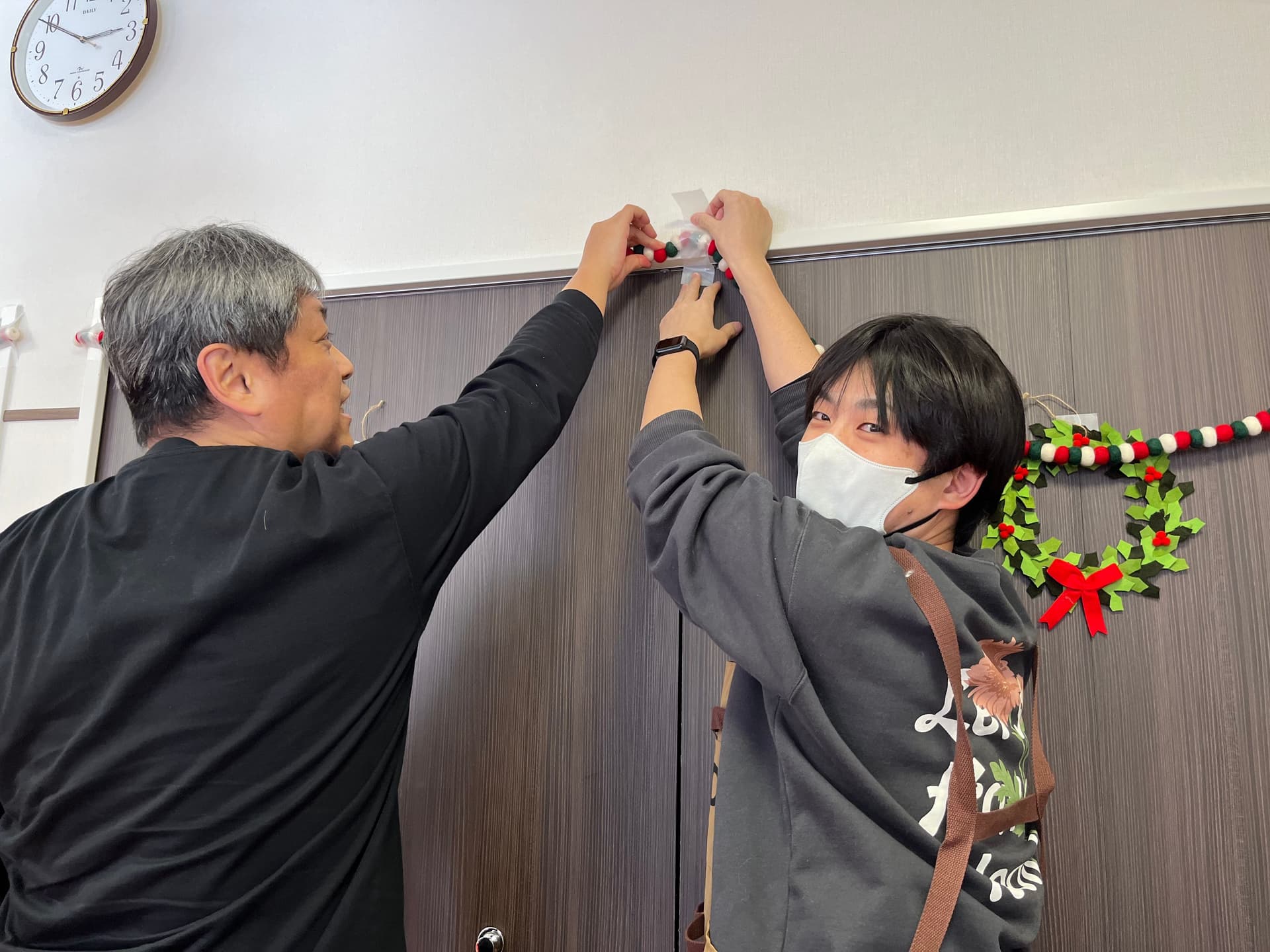 two men are decorating a door with christmas decorations .
