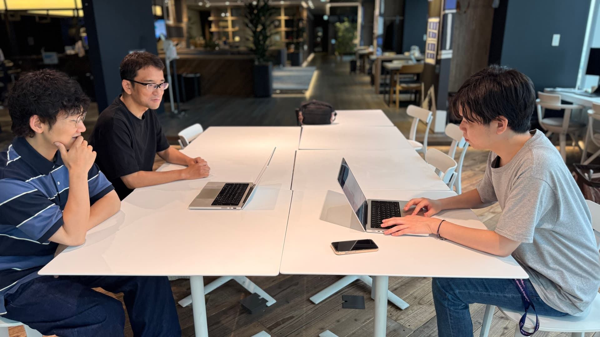 a group of people are sitting at a table with laptops .