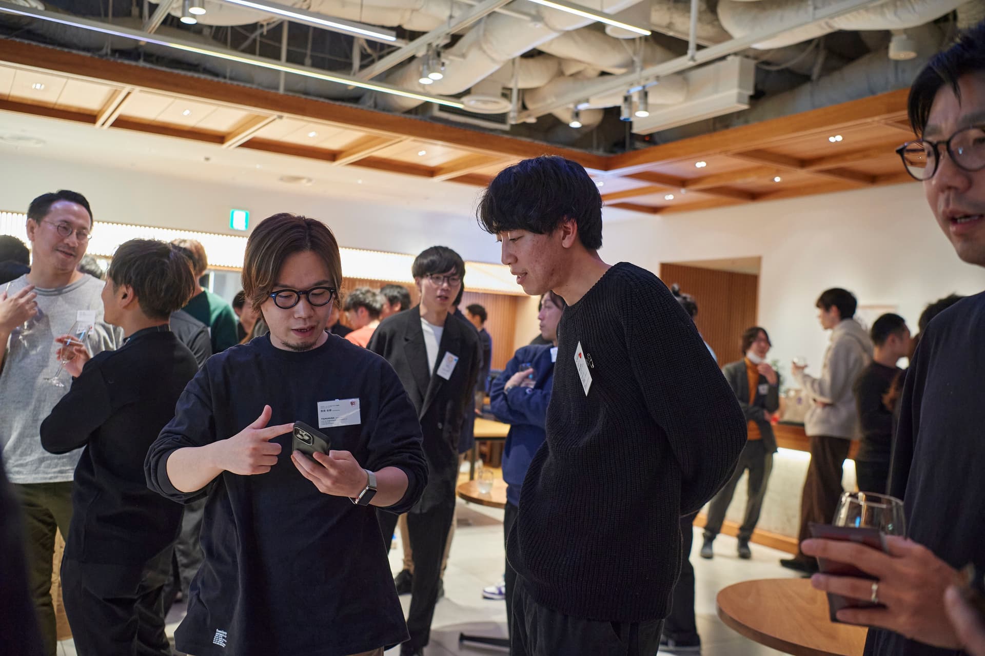 a group of people are standing in a room looking at their phones .